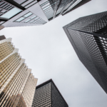 From the ground, looking up skyscrapers against a cloudy sky.